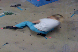 Ein Kind beim Bouldern auf einer Wand.