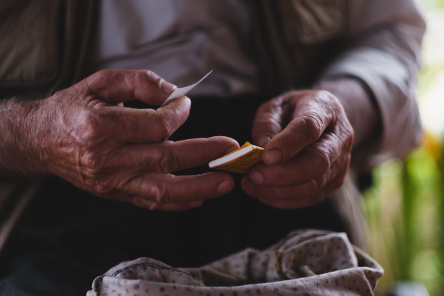 Alter Mann hält ein Blatt Papier, sieht besorgt aus, mit unscharfem Hintergrund.