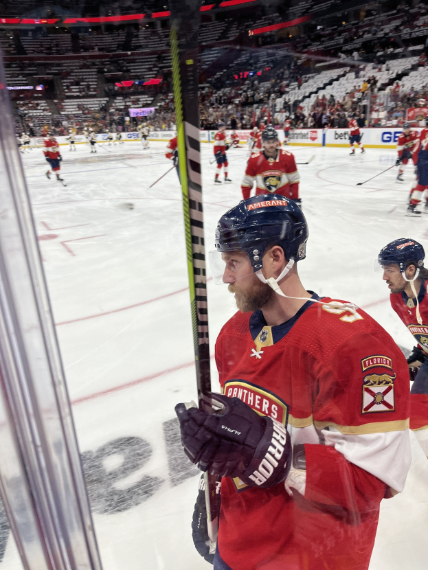 Gruppe von Hockey-Spielern mit Helmen und Handschuhen auf dem Eis mit Hockey-Schläger, die Tribüne mit Zuschauern und Plakate mit "Florida Panthers vs New Jersey Devils - 3/24/15 NHL Pick, Odds, and Prediction".