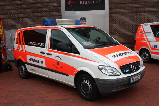Zwei Rettungswagen nebeneinander vor einem Gebäude geparkt, mit einem Feuerlöscher links sichtbar.