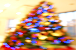 Ein unscharfer Innenraum-Aufnahme mit einem Weihnachtsbaum in der Mitte, der mit Lichtern und Schmuck verziert ist.