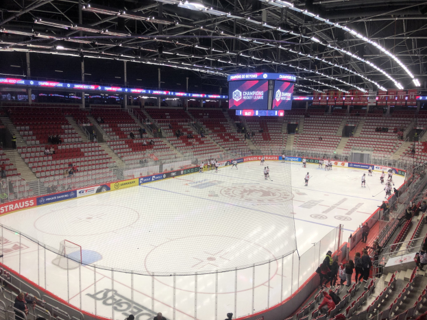 Eishockeyspiel in einer großen Arena zwischen den St. Louis Blues und Detroit Red Wings, mit Zuschauern auf den Sitzen und Stehplätzen in der Nähe des Spielfelds, umgeben von einem Zaun und einem Display.