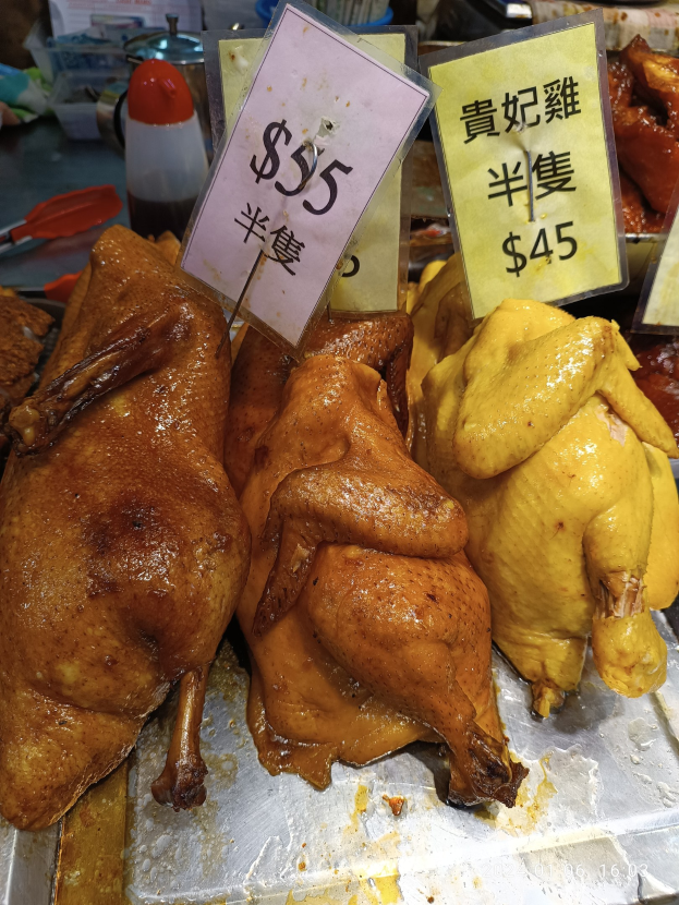 Hühnervorführungen auf einem Metalltablett mit Preisschildern in einer Marktsituation.