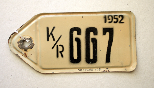 Weiße Fläche mit einer angebrachten Nummernschild, das alphanumerische Texte anzeigt.