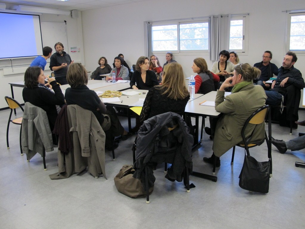 Eine Gruppe von Menschen, die sich unterhält und diskutiert, wobei zwei andere Personen separat stehen und sprechen.