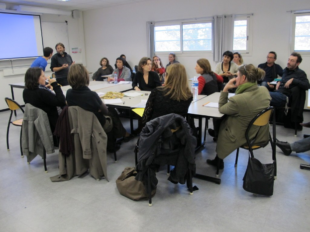 Eine Gruppe von Menschen, die sich unterhält und diskutiert, wobei zwei andere Personen separat stehen und sprechen.