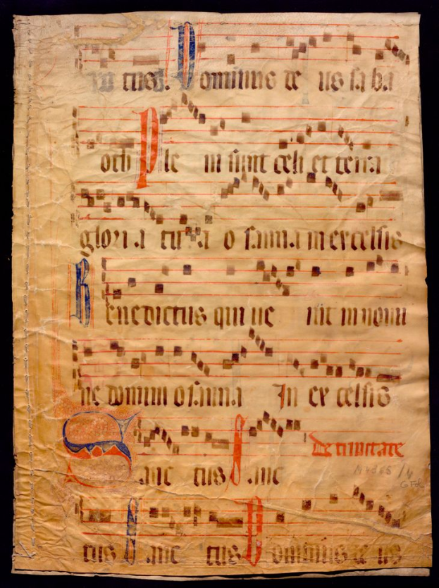 Ein illuminiertes Manuskript mit Musiknotation auf einem Blatt Papier vor dunklem Hintergrund, gefüllt mit Text und Musiksymbolen, die ein komplexes Design bilden.