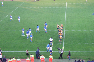 Eine Gruppe von Menschen auf einem Fußballfeld, wobei eine Person eine Videokamera hält.