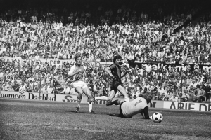 Schwarzes Foto von Fussballspielern in Aktion auf einem Feld mit Zuschauern im Hintergrund und einer "Bundesliga 1978-79 Ajax 1-1 Hannover 96"-Aufschrift.
