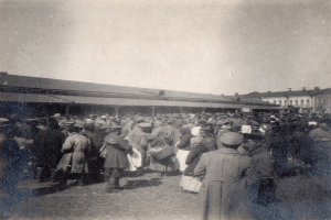 Eine große Menschenmenge, die wie Flüchtlinge aussieht, steht vor einem Gebäude an einem klaren Himmel, dargestellt in Schwarz-Weiß.