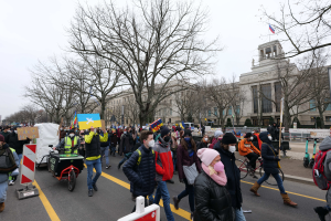 Eine große Gruppe von Menschen marschiert auf einer Straße in Washington, D.C. am 21. Januar 2020 mit Schildern und Transparenten, während einige Fahrräder fahren, Schilder, Bäume und ein klarer blauer Himmel im Hintergrund zu sehen sind.