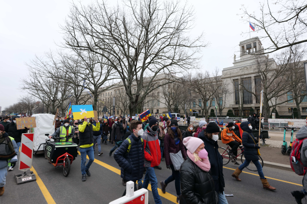 Eine große Gruppe von Menschen marschiert auf einer Straße in Washington, D.C. am 21. Januar 2020 mit Schildern und Transparenten, während einige Fahrräder fahren, Schilder, Bäume und ein klarer blauer Himmel im Hintergrund zu sehen sind.