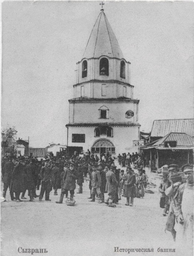 Schwarzes und weißes Foto einer Gruppe von Menschen, die vor der Intercession Church auf dem Nerl stehen, mit Häusern und Bäumen im Hintergrund.
