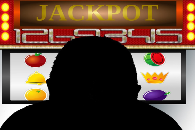 Ein Mann spielt ein Online-Slot-Spiel mit "Jackpot" auf einem Bildschirm mit Obst-themen und Text auf einer Tafel.