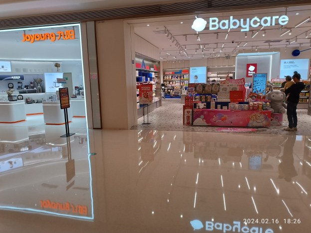 Babycare-Laden-Innenansicht im Mall of Asia mit Regalen voller Gegenstände, Spielzeug, Schildern und Deckenleuchten sowie Menschen, die durchstöbern.