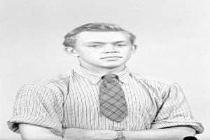 Ein Schwarz-Weiß-Foto eines Mannes in Hemd, Krawatte und einer Uhr am Handgelenk.