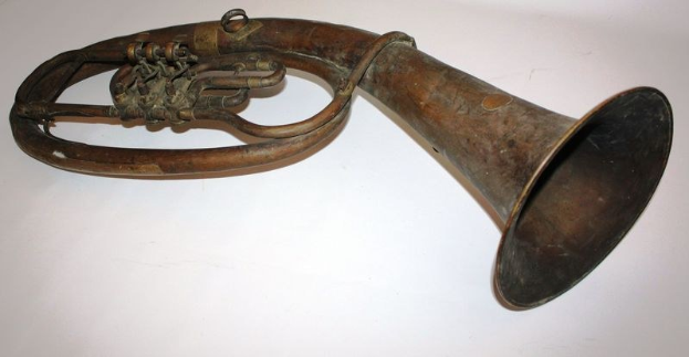 Alter Messinghorn mit glänzendem Finish und kunstvollen Gravuren, mit einem gebogenen Hals und einem aufgeblähten Ende auf einem weißen Hintergrund.