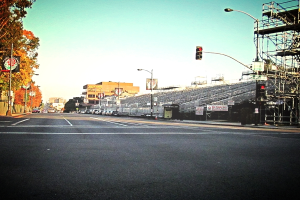 Eine Straße mit einem Verkehrssignalmast und Gerät auf der rechten Seite, Warnschilder und mehrere Fahrzeuge auf der linken Seite und Bäume im Hintergrund.