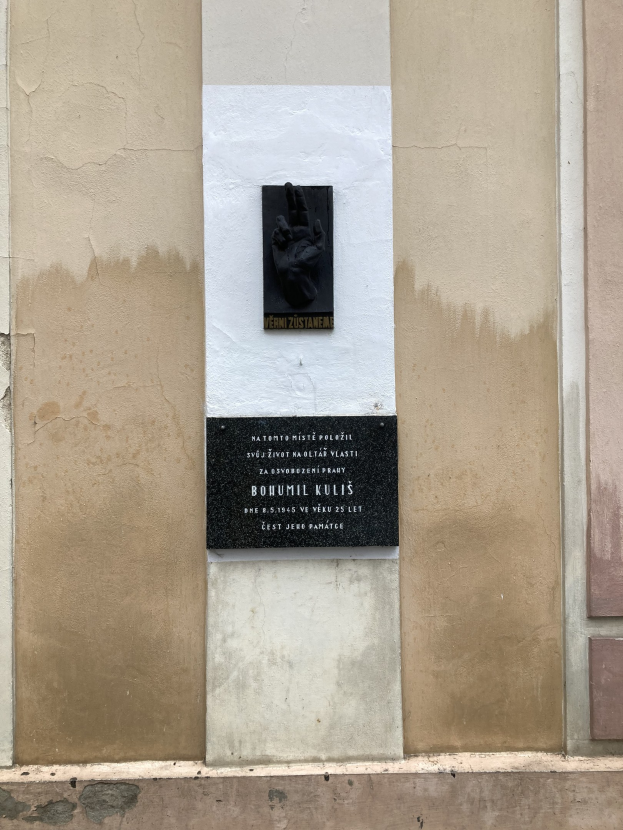 Schwarze Tafel an einem Gebäude mit einer Hand darauf, die mit Text beschriftet ist, der Holocaust-Opfern gedenkt.