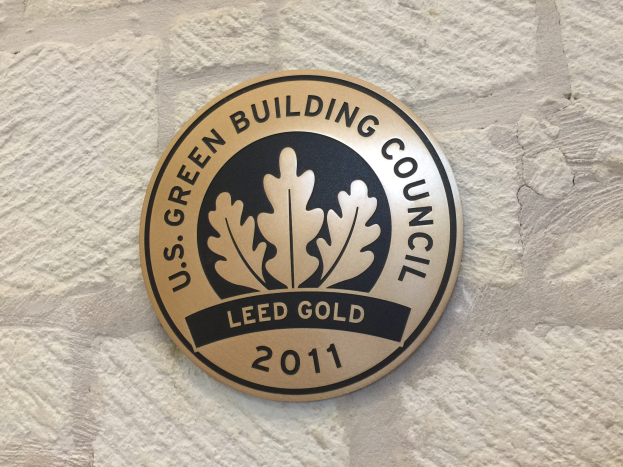Logo der U.S. Green Building Council an einer Gebäudefassade, bestehend aus einem grünen Schild mit weißer Umrandung, schwarzer Schrift und einem umgebenden Lorbeerkranz.