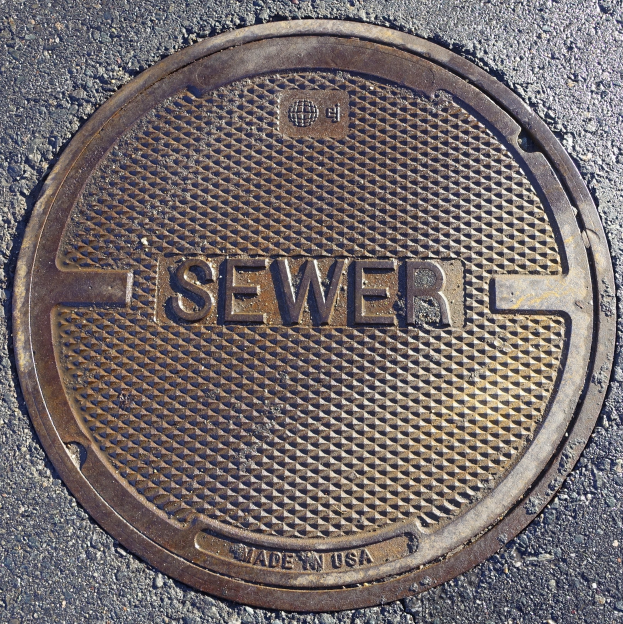 Metallschachtdeckel auf der Straße mit der Aufschrift "Kanal"