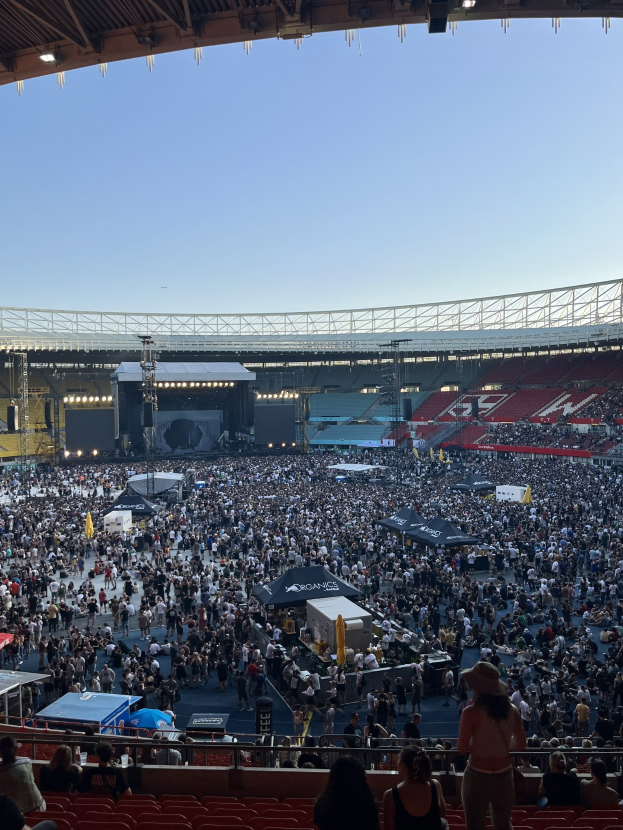 Große Menschenmenge auf einem Stadion mit Zelten, Geländern und Überdachung, was auf ein Konzert in der O2 Arena in London hindeutet.