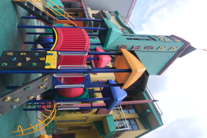 Ein buntes Kinderspielplatzgerät zum Verkauf, das vor einem Gebäude mit Fenstern steht, umgeben von Bäumen und einem bewölkten Himmel.