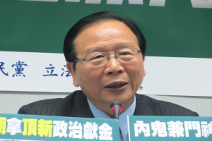 Ein Mann im Anzug und Krawatte spricht vor einer Tafel mit Text in ein Mikrofon.