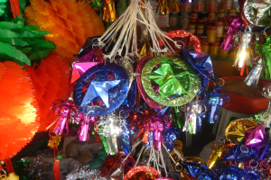 Bunte Dekorationen, darunter Laternen und Bänder, hängen von der Decke, mit Flaschen auf Gestellen im Hintergrund.