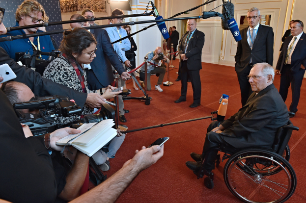 Ein Mann im Rollstuhl wird von Reportern mit Kameras, Handys und Mikrofonen umgeben.