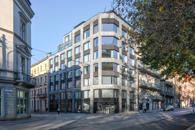 Großes mehrstöckiges Bürogebäude mit zahlreichen Fenstern, umgeben von Straßeninfrastruktur, Fahrzeugen, Fußgängern, Bäumen und einem bewölkten Himmel, das als neue Firmenzentrale dient.