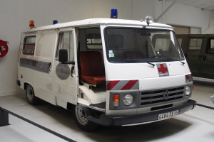 Ein Rettungswagen steht in einem Gebäude mit einem Feuerlöscher an der Wand links daneben.